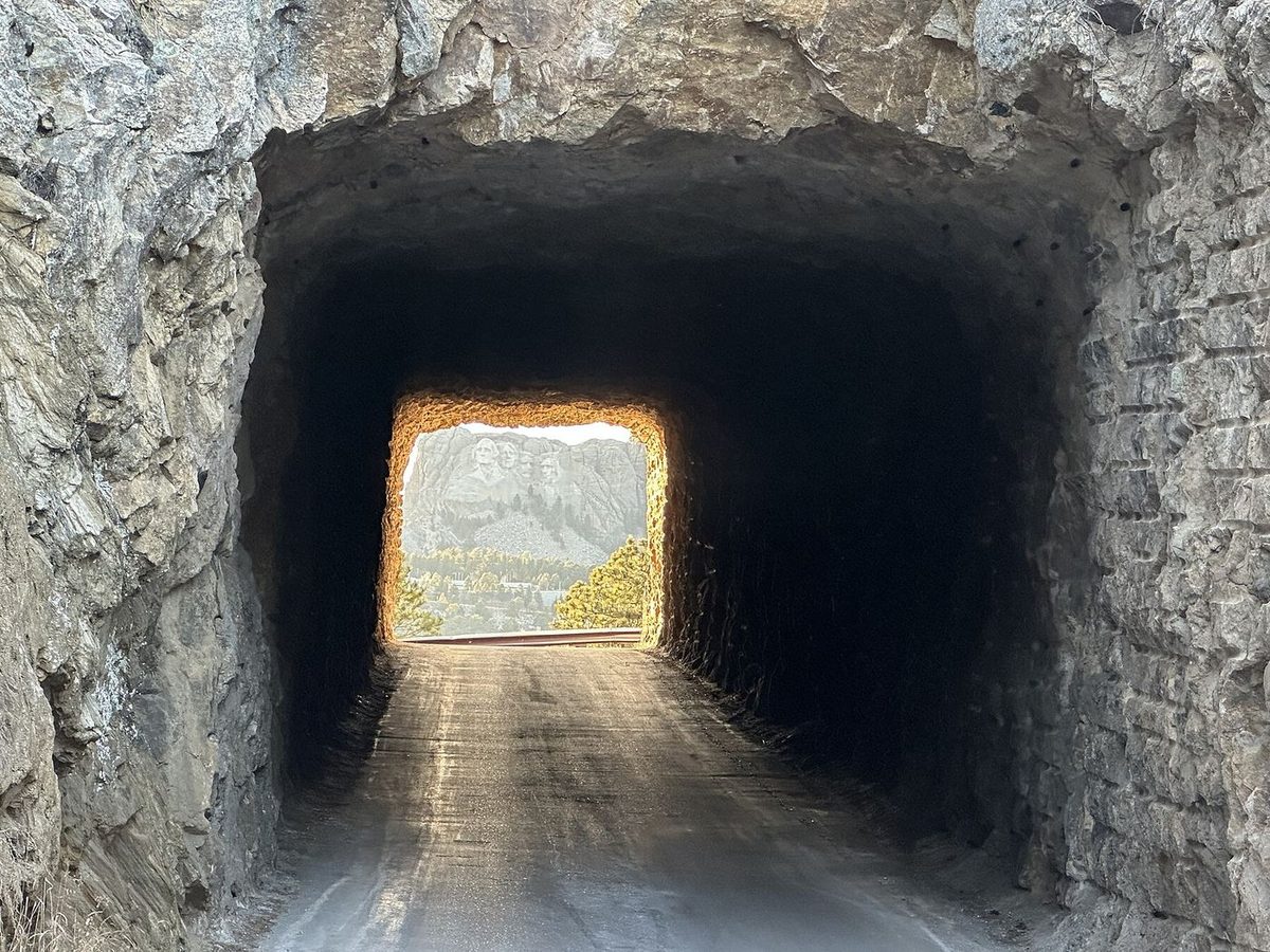 Mount Rushmore framed by a narrow rock tunnel on Iron Mountain Road
