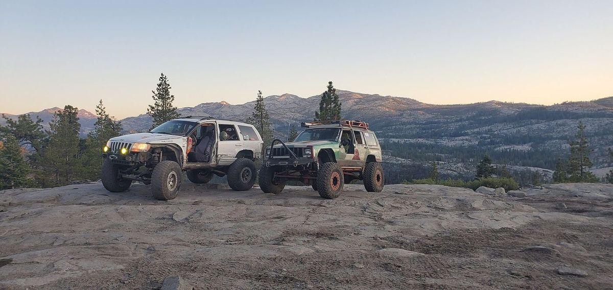 Two built Jeep Cherokees parked on Sierra granite above the Rubicon at dusk